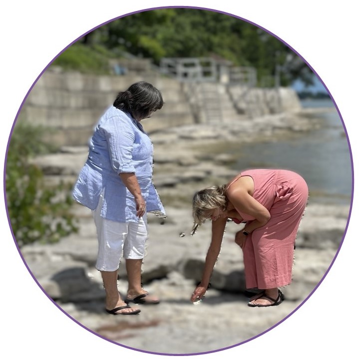 Two women are discovering natural items on a rock beach.