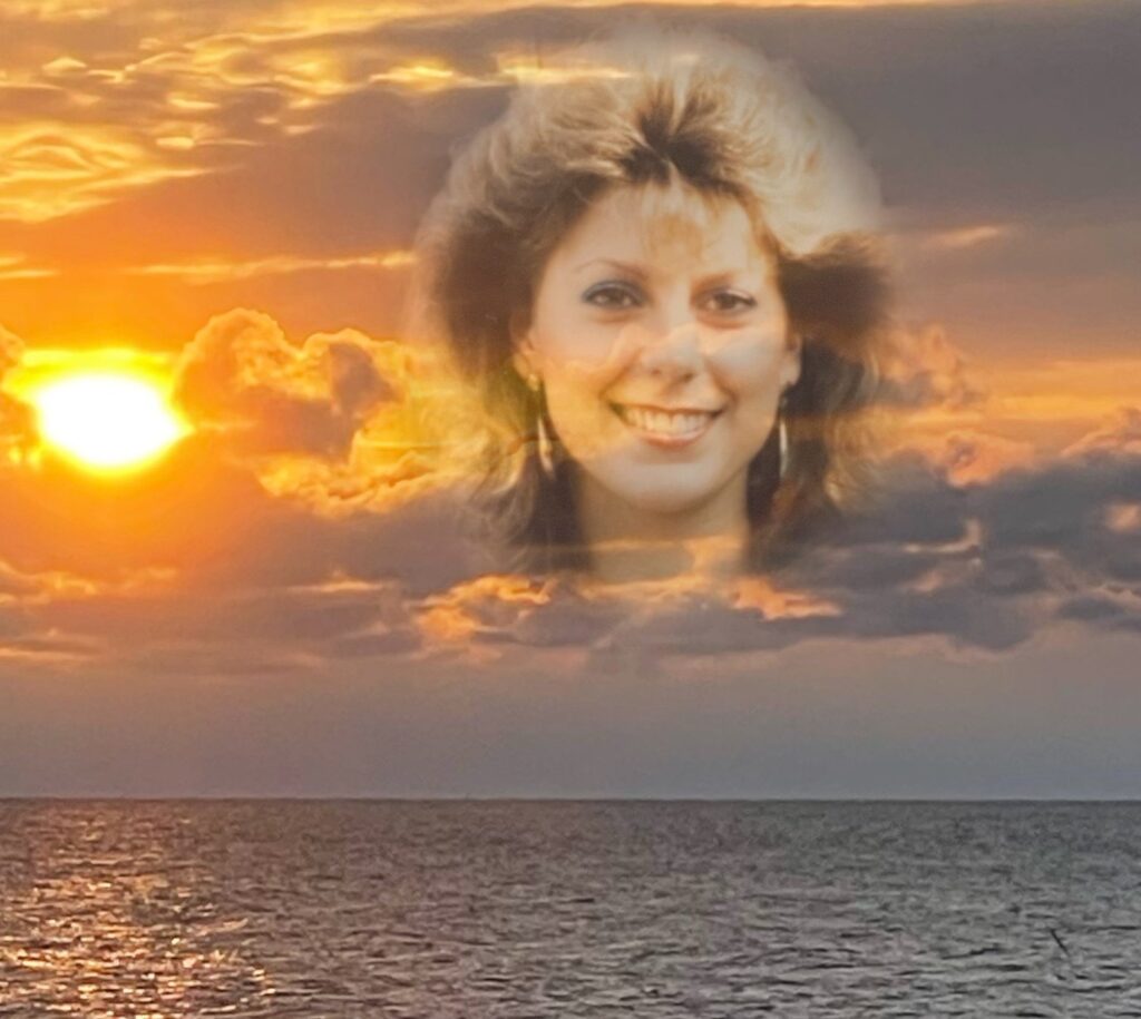 An photo of my sister Laurie is superimposed over an image of a beautiful sunrise over water.